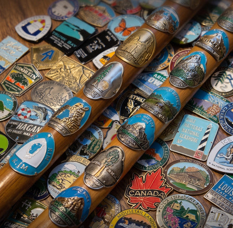 Collection of Hike America hiking stick medallions displayed on wooden hiking staffs